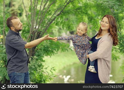 Mom and young daughter and dad, a young family on a walk in the park in summer