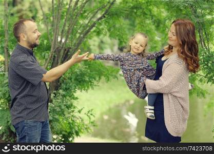 Mom and young daughter and dad, a young family on a walk in the park in summer