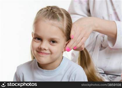 Mom braids long hair elastics cute six year old daughter. Mom braids tails of hair six-year daughter