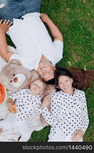 Mom, dad and daughter lying on the picnic with teddy bear. The concept of summer holiday. Mother&rsquo;s, father&rsquo;s, baby&rsquo;s day. Family spending time together on nature. Family look.. Mom, dad and daughter lying on the picnic with teddy bear. The concept of summer holiday. Mother&rsquo;s, father&rsquo;s, baby&rsquo;s day. Family spending time together on nature. Family look