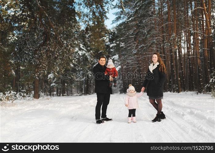 mom, dad, daughter and little son having fun in the winter forest. Active parents with children run in the snowy forest.. mom, dad, daughter and little son having fun in the winter forest. Active parents with children run in the snowy forest