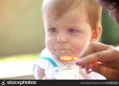 Mom feeds a little baby a spoon