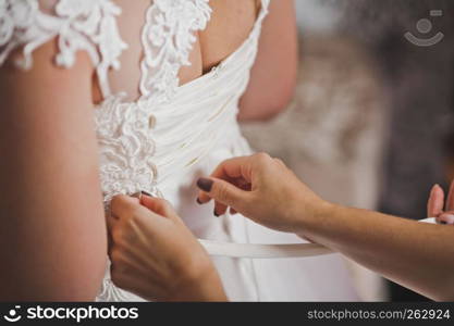 Mom helps her daughter to wear a wedding dress.. Mothers hands fasten wedding dress on her daughter 1943.