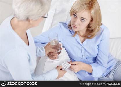 Mom holds out her daughter pills and a glass of water