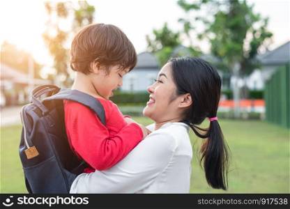 Mom hug and carry her son. Preparing to send her children back to school in morning. Mother playing with kids. Education and Back to school concept. Happy family and Loving of people theme