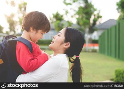 Mom hug and carry her son. Preparing to send her children back to school in morning. Education and Back to school concept. Happy family and Loving of people theme