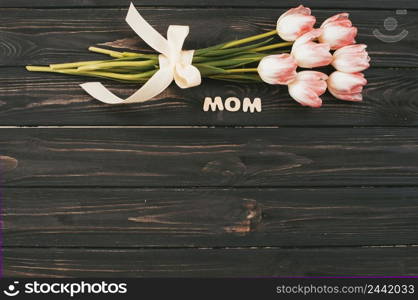 mom inscription with tulips bouquet dark table