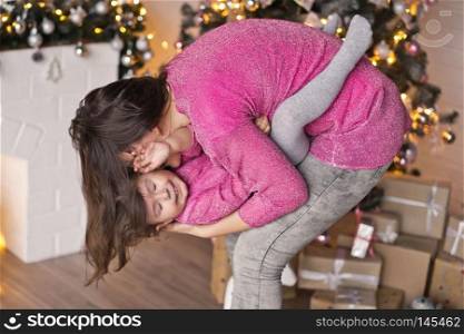 Mom is circling a girl in his arms on the background of the party.. Girl playing with mother on the background of Christmas decorations ligh