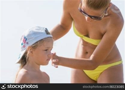 Mom misses on the beach little girl&amp;#39;s face sunscreen