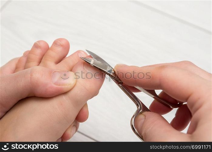 Mom mows the toenails of the child, close-up