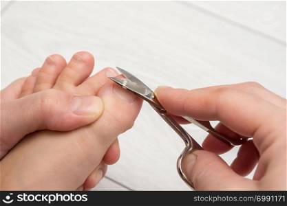 Mom mows the toenails of the child, close-up