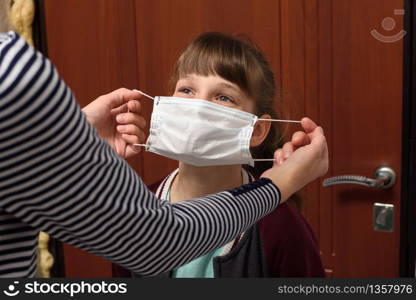 Mom puts on a child a medical protective mask before leaving the house