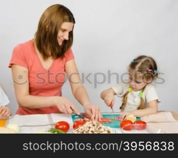 Mom teaches daughter to a six-year cut with a knife products for cooking at the kitchen table