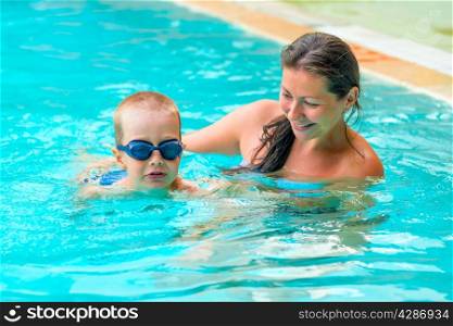 Mom teaches son to swim in the pool
