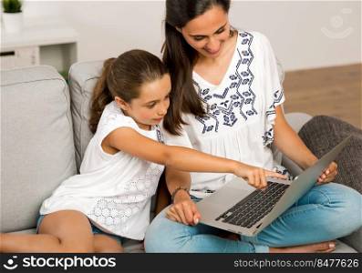 Mom teaching Daughter working with a a laptop at home