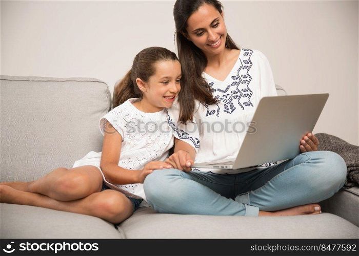 Mom teaching Daughter working with a a laptop at home9