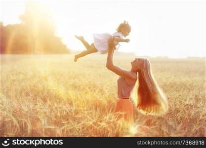 Mom throws up a daughter in a field on his hands