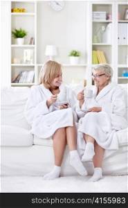 Mom with grown-up daughter tea on the couch