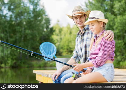 Moments of family togetherness. Father and daughter sitting on bridge and fishing
