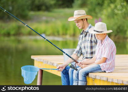 Moments of family togetherness. Father and son sitting on bridge and fishing