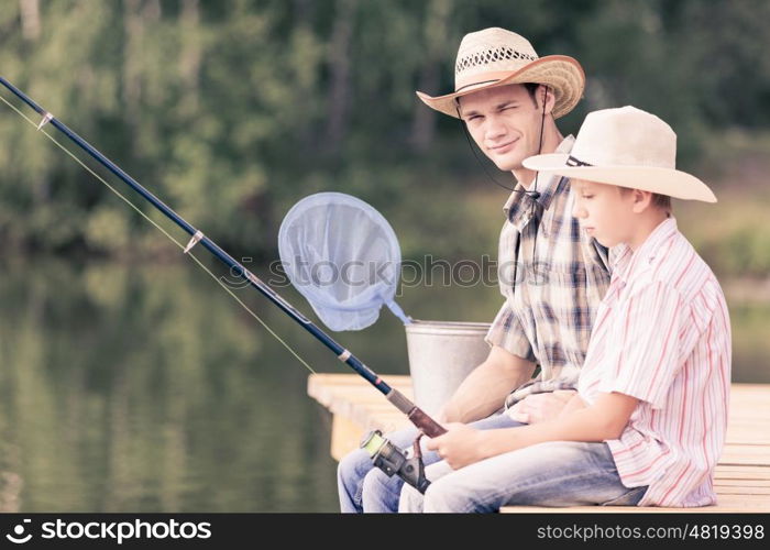 Moments of family togetherness. Father and son sitting on bridge and fishing