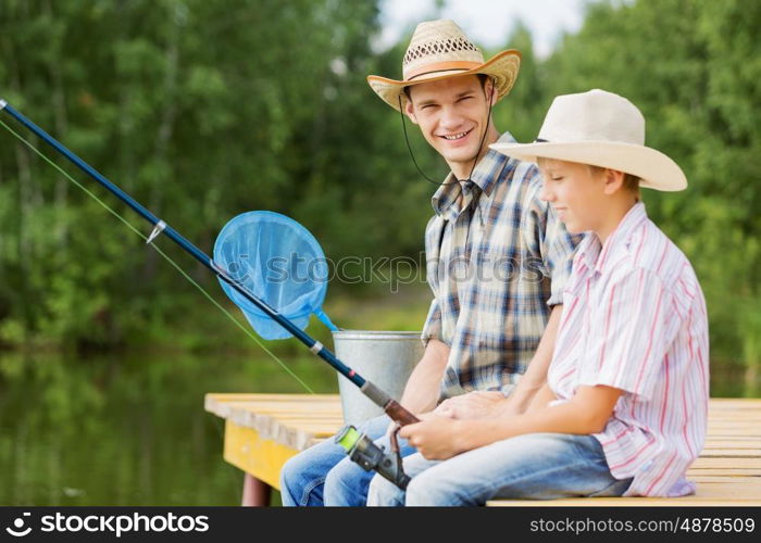 Moments of family togetherness. Father and son sitting on bridge and fishing