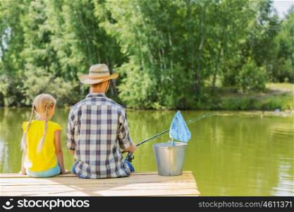 Moments of family togetherness. Rear view of father and daughter sitting on bridge and fishing