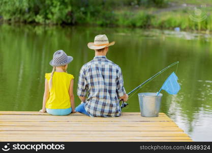 Moments of family togetherness. Rear view of father and daughter sitting on bridge and fishing