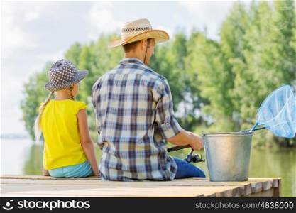 Moments of family togetherness. Rear view of father and daughter sitting on bridge and fishing