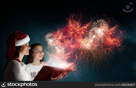 Moments of family togetherness. Young mother and daughter read book and light coming out of pages