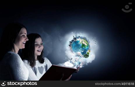 Moments of family togetherness. Young mother and daughter read book and light coming out of pages. Elements of this image are furnished by NASA