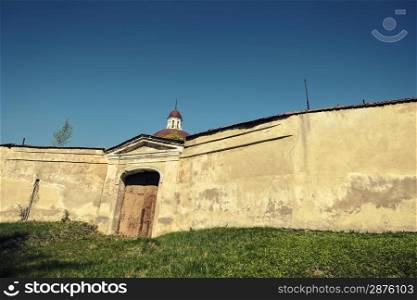 Monastery gate. Monastery on the green hill with closed gate in a high wall