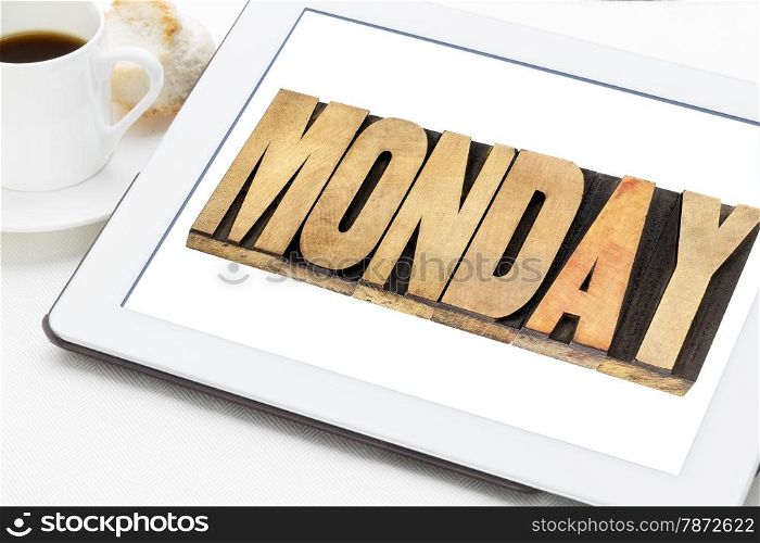 Monday - a word in letterpress wood type on digital tablet with a cup of coffee.