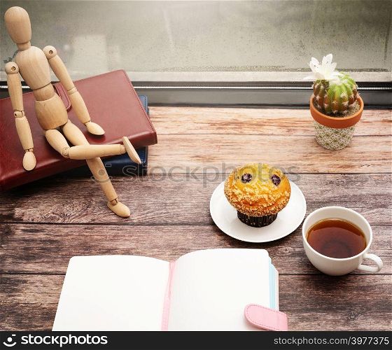 Monday Morning Concept, Hot tea and muffin cake on wooden workspace near window