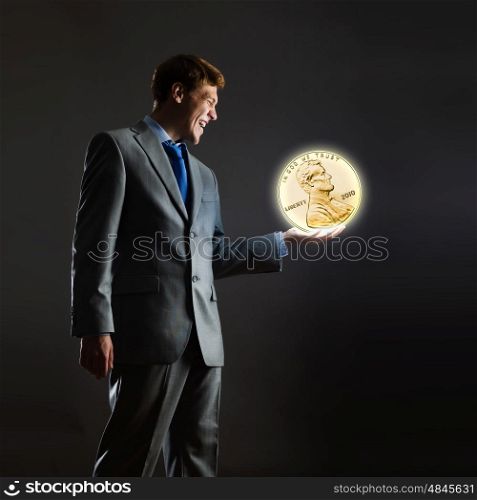 Monetary concept. Businessman holding huge cent coin in hand