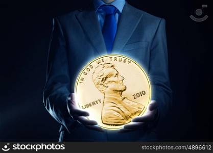 Monetary concept. Businessman holding huge cent coin in hand