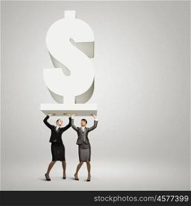 Money concept. Image of two businesswomen holding dollar sign above head