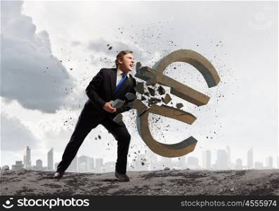 Money concept. Young businessman breaking stone euro sign. Currency concept