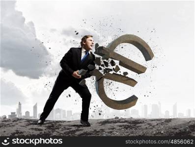 Money concept. Young businessman breaking stone euro sign. Currency concept
