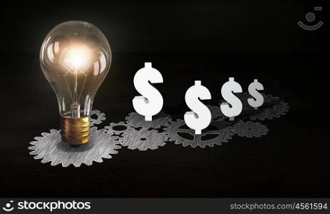 Money earning machine. Gears mechanism and glowing light bulb on adrk background