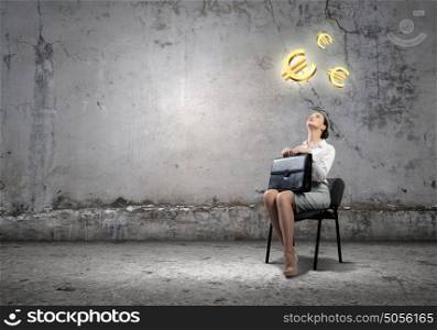 Money exchange. Image of businesswoman sitting on chair with suitcase in hands looking at euro symbols above