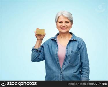 money, finance and old people concept - portrait of smiling senior woman with credit card over blue background. portrait of smiling senior woman with credit card