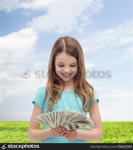 money, finances and people concept - smiling little girl looking at dollar cash money