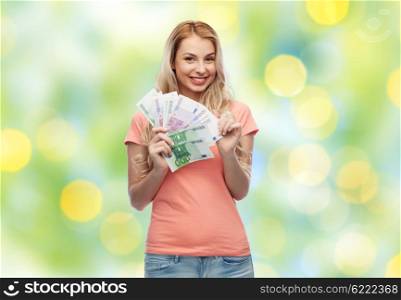money, finances, investment, saving and people concept - happy young woman with euro cash money over summer green lights background