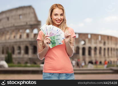 money, finances, travel, tourism and people concept - happy young woman with euro cash money over coliseum background