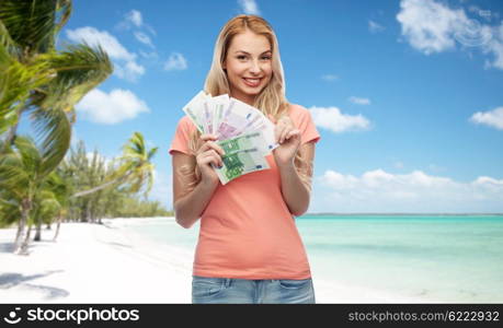 money, finances, travel, tourism and people concept - happy young woman with euro cash money over exotic tropical beach with palm trees background