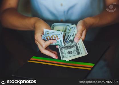 Money in human hands, women counting a lot of 100 dollars, with business folders , on a black background