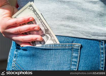 Money in pocket. Woman hand putting money in jeans pocket