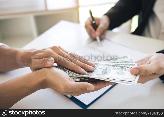 Money in the hands of businessmen who are submitting to entrepreneurs to force the signing of contract documents about corruption concept.