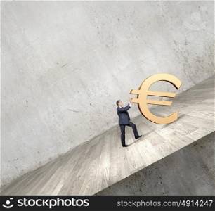 Money making. Businessman rolling euro sign up the hill